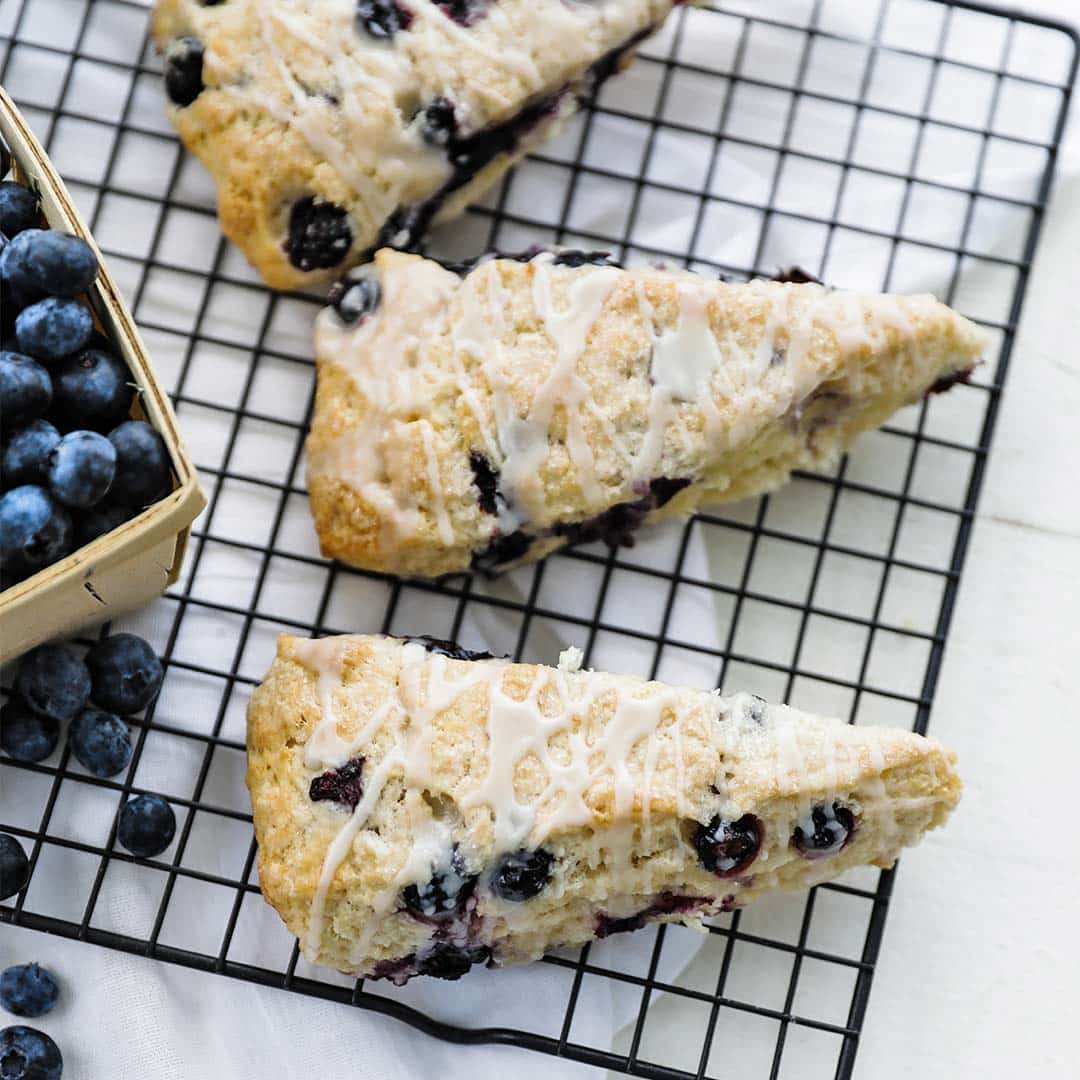 blueberry scones on a cooling rack with blueberries