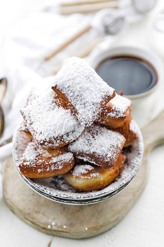 bowl of beignets dusted heavily with powdered sugar