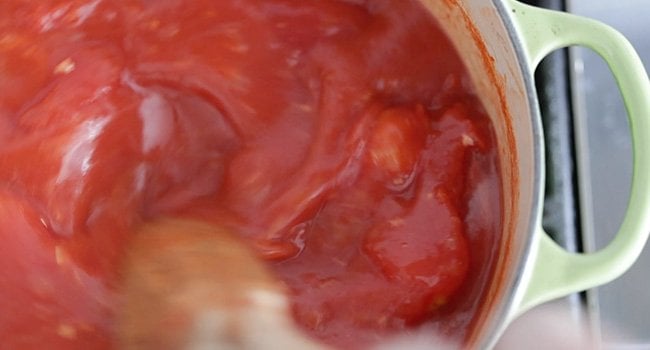 stirring tomatoes in a pot