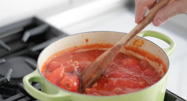 adding vinegar to a pot of tomatoes