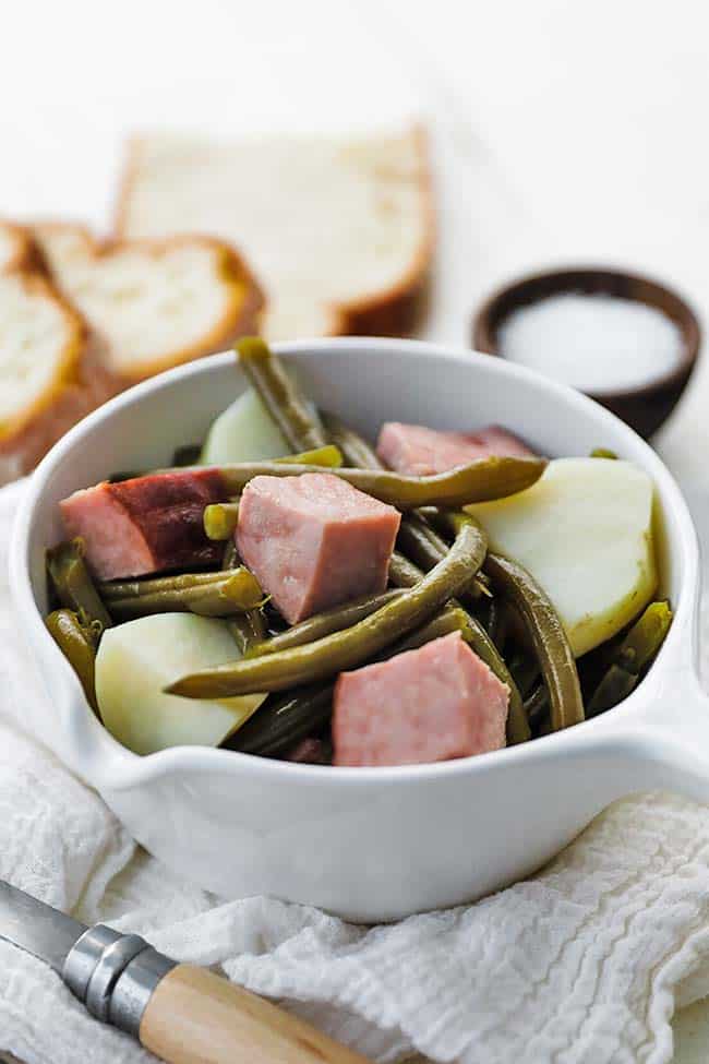 bowl of chunks of ham, green beans and potatoes with bread