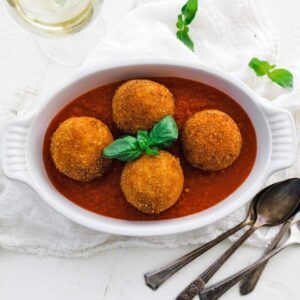 casserole dish with fried arancini balls and tomato sauce