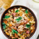 bowl of pasta fagioli with herbs, bread and white wine