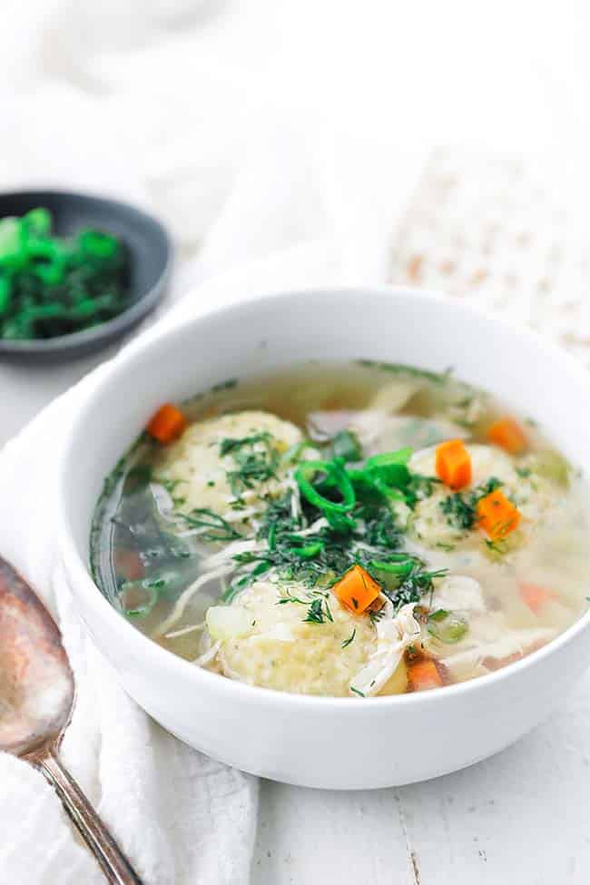bowl of matzo ball soup with carrots and dill