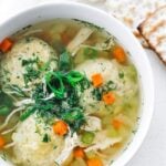 3 matzo balls in a chicken soup broth with dill and green onions