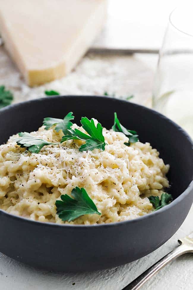 creamy parmesan risotto with parsley leaves and cheese pepper on top