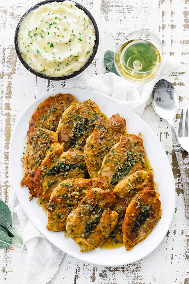 chicken saltimbocca on a platter with white wine and mashed potatoes