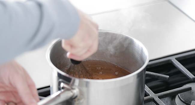 whisking together apple cider with salt and sugar in a pot