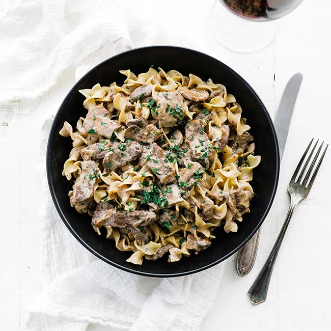 bowl of egg noodles with beef stroganoff and sauce
