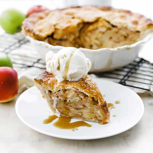 sliced of apple pie on a plate with ice cream and caramel sauce