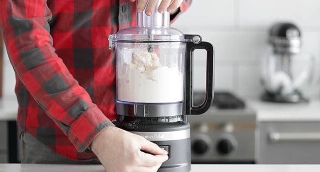 adding dry ingredients to a food processor