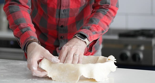 adding dough to a pie pan