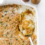 a spoon in a dish of potatoes au gratin
