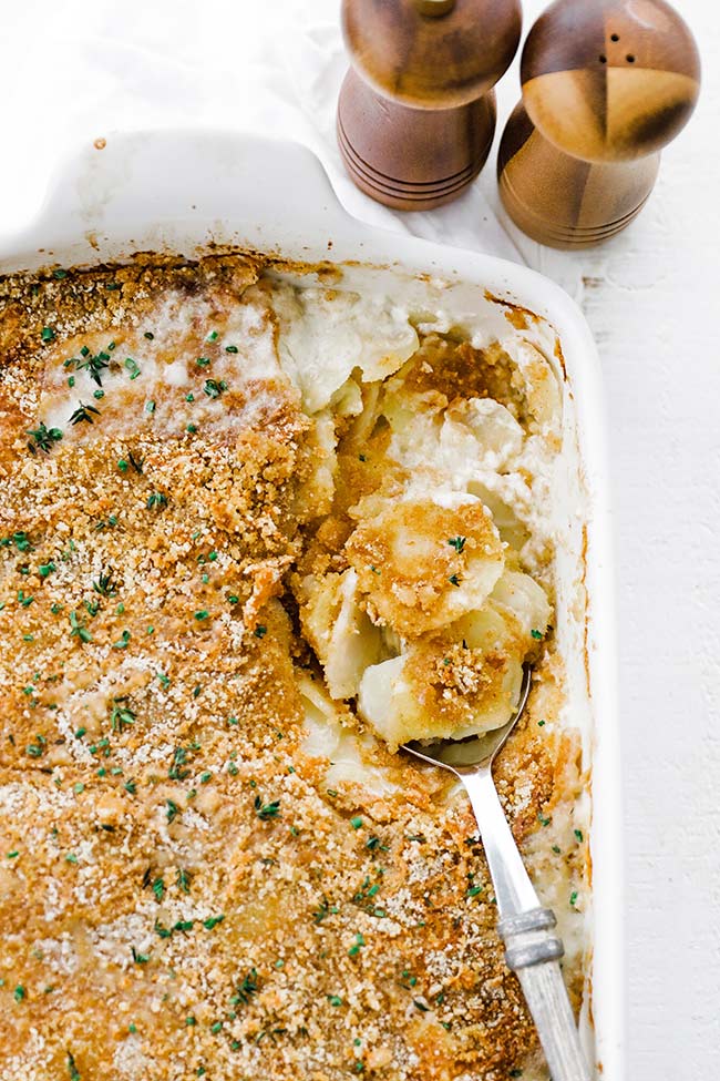 a spoon in a dish of potatoes au gratin