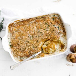 casserole dish full of potatoes au gratin with a spoon
