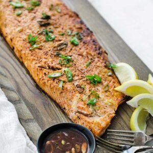 cooked salmon on a cutting board with herbs and lemons