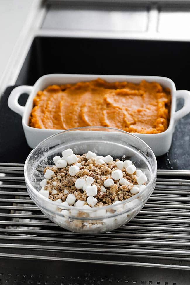 pecan and marshmallow topping in a bowl next to mashed sweet potatoes in a casserole dish