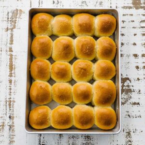 pan full of cooked and buttered dinner rolls