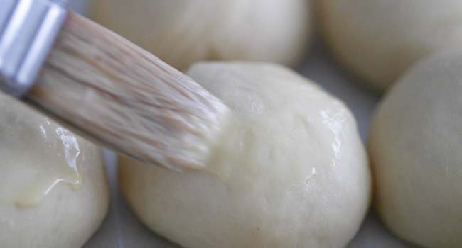 brushing a dough ball with a whisked egg