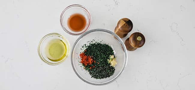 bowl of chopped herbs with oil and vinegar