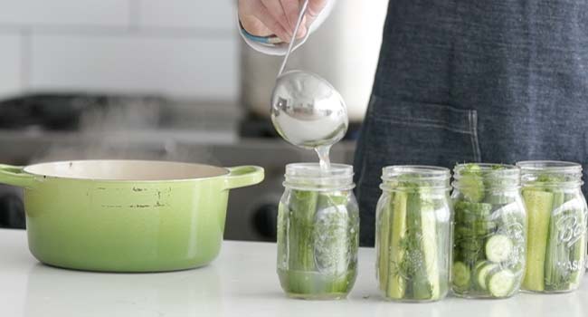 adding brine to a jar of pickles