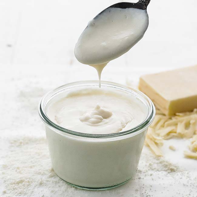 jar of white cheesy sauce with a spoon in it