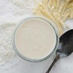 jar of mornay sauce with a spoon and cheese
