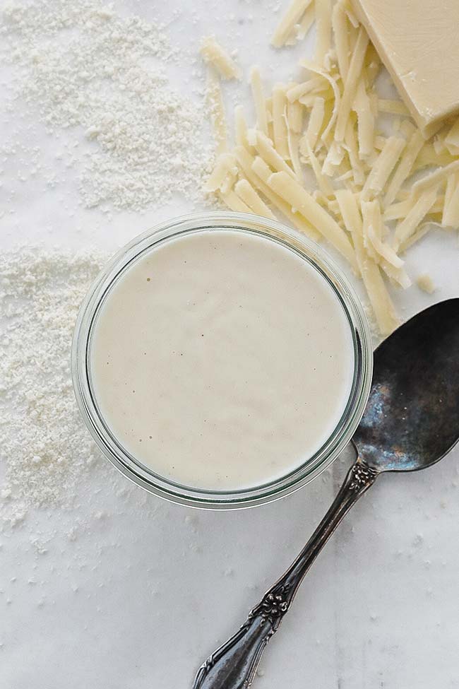 jar of mornay sauce with a spoon and cheese