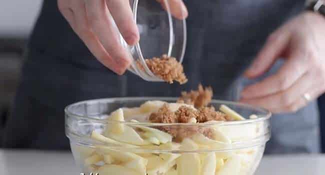 adding brown sugar to a bowl of apples