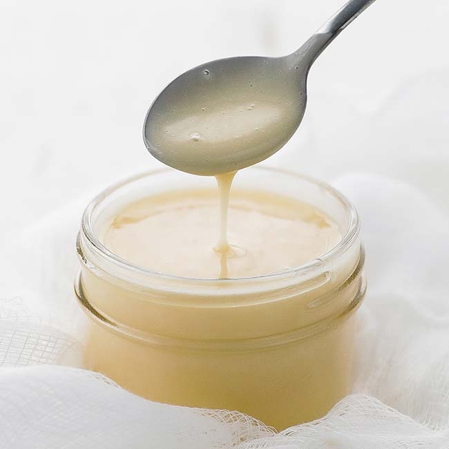dipping a spoon in a jar of beurre blanc