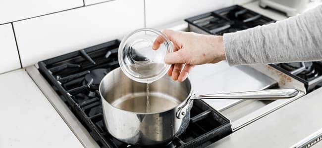 pouring in vinegar to a sauce pot