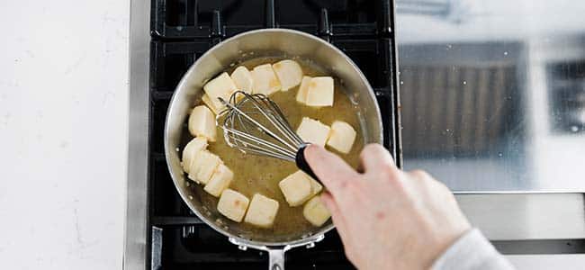 whisking the chunks of butter into a sauce
