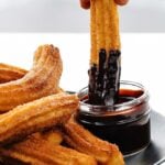 dipping a churro into chocolate sauce