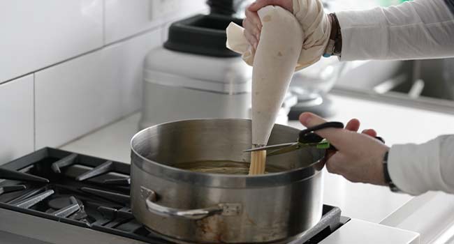 adding churro dough into frying oil