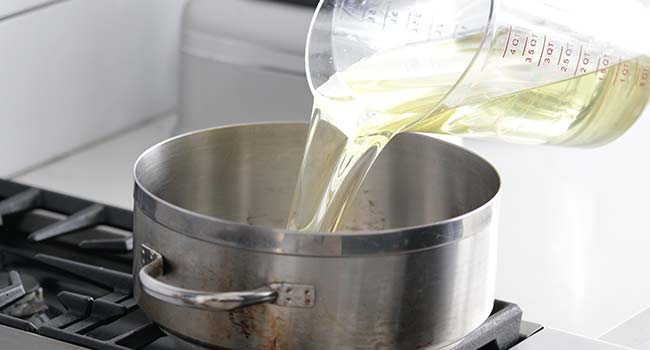 adding oil to a pot for frying