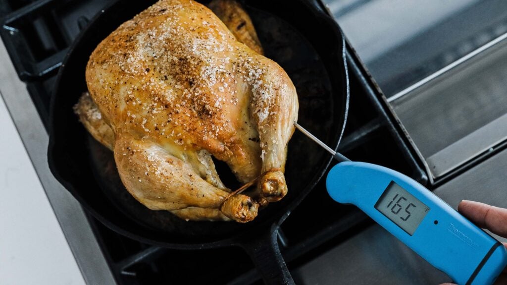 checking the temperature of the chicken with a thermometer