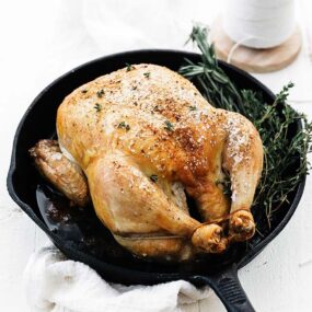 whole roast chicken with herbs in a cast iron pan