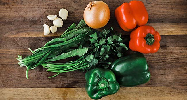 cutting board with peppers, onions, cilantro and garlic