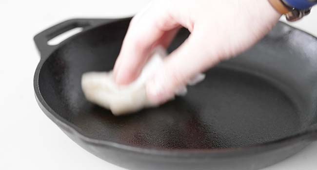 adding oil to a pan with a paper towel