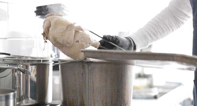 removing cooked poached chickens from a pot