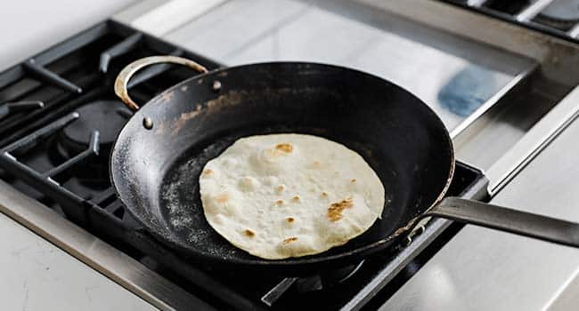 cooking a flour tortilla in a large pan