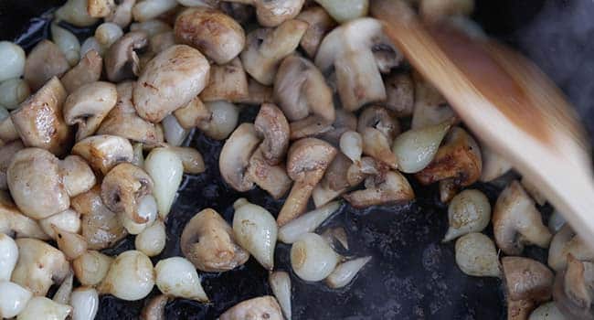 cooking mushrooms and onions in a pan