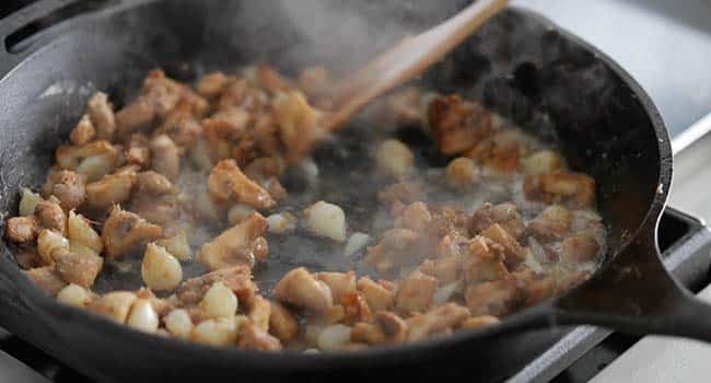 stirring wine with vegetables in a pan