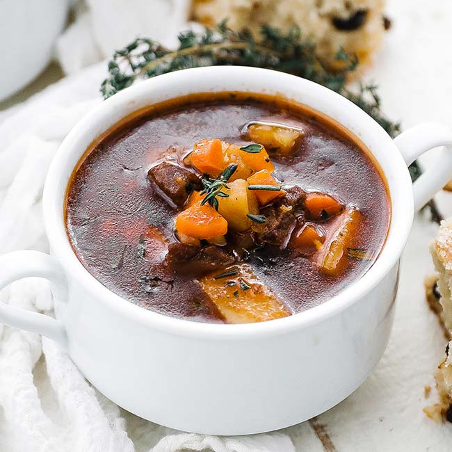 cup of beef stew with fresh herbs