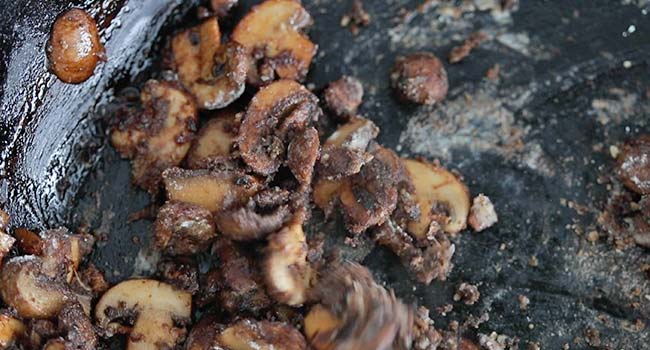 cooked mushrooms in a pan coated in flour