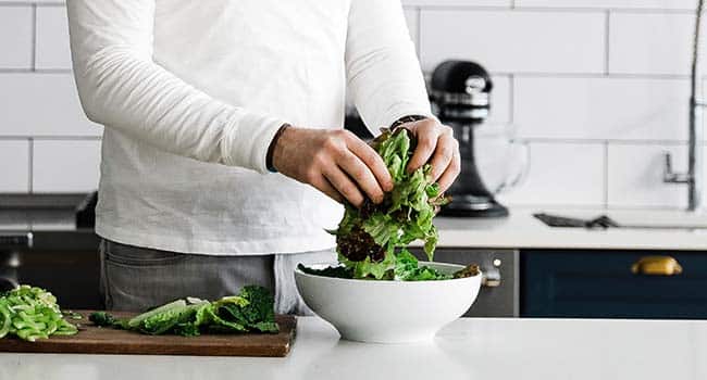 adding greens to a large bowl