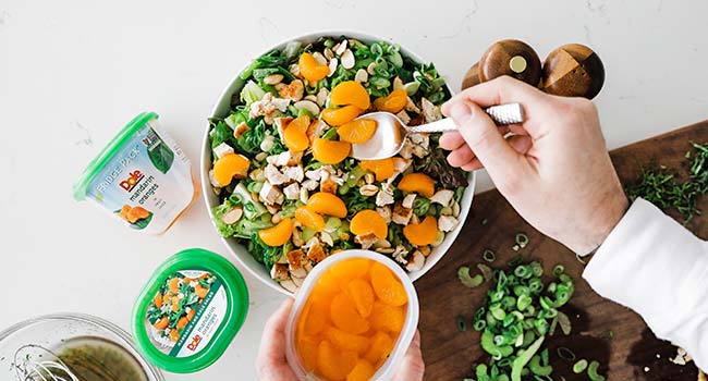 adding dressing to a mandarin orange salad