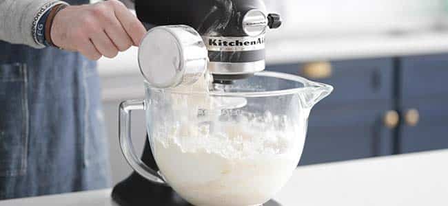 adding flour to a stand mixer