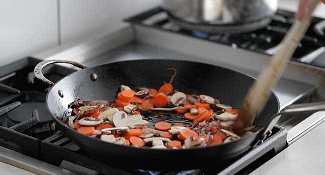 cooking carrots and onions in a frying pan