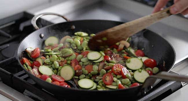 cooking zucchini and asparagus in a primavera pasta